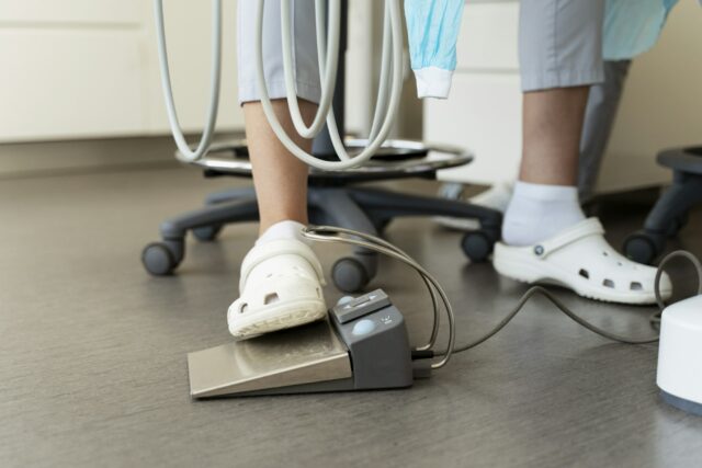 Cropped view of the doctor dentist in special shoes pressing the pedal of the dental unit