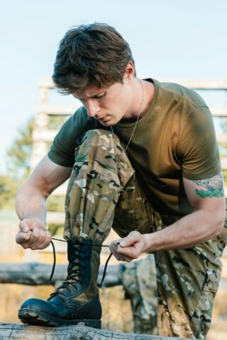 portrait of soldier in military uniform tying shoelaces